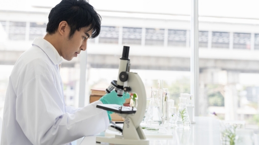 Asian man scientists tests of plants with microscope and glassware in laboratory. Scientists doing analysis for germs and bacteria in the laboratory. Researcher and discovery concept