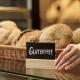 Closeup of fresh breads in artisan bakery with female hand holding gluten free sign, copy space