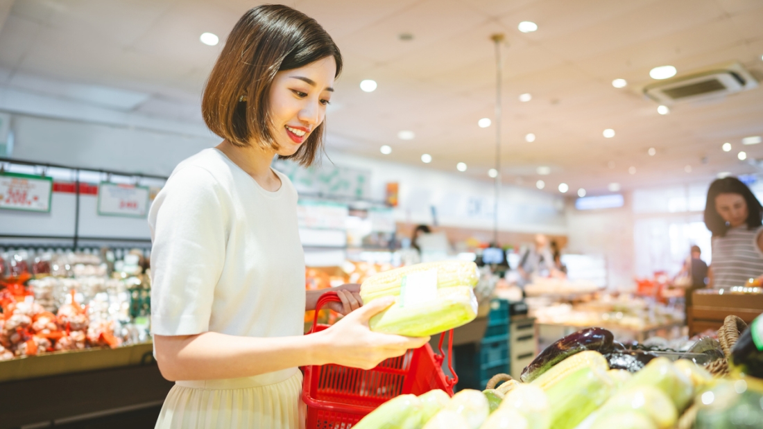 Consumer shopping at supermarket concept. Young adult asian woman customer choosing organic vegetable product from shelf. Consumer buying at grocery store lifestyles.