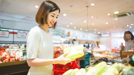 Consumer shopping at supermarket concept. Young adult asian woman customer choosing organic vegetable product from shelf. Consumer buying at grocery store lifestyles.