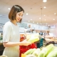 Consumer shopping at supermarket concept. Young adult asian woman customer choosing organic vegetable product from shelf. Consumer buying at grocery store lifestyles.