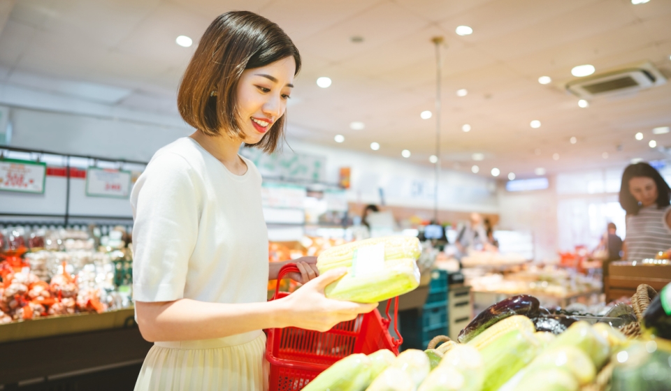 Consumer shopping at supermarket concept. Young adult asian woman customer choosing organic vegetable product from shelf. Consumer buying at grocery store lifestyles.