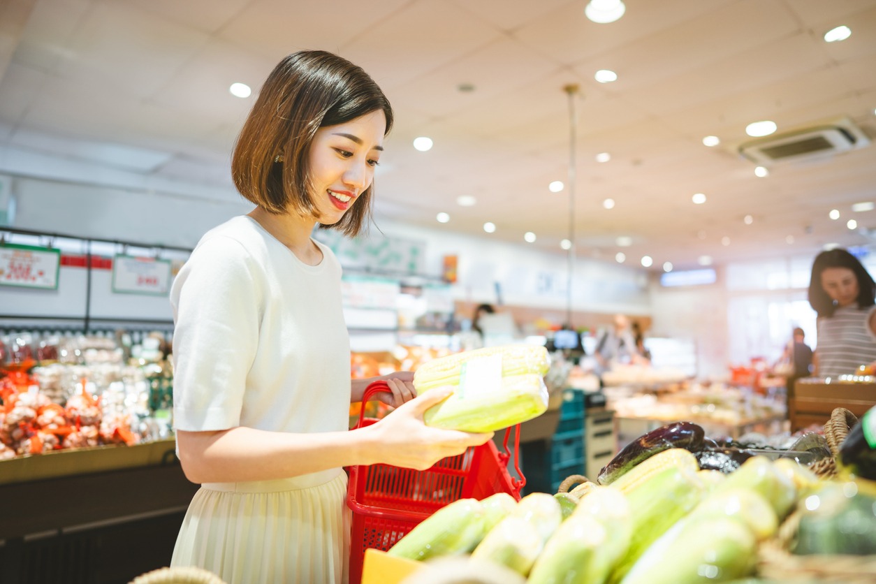 Consumer shopping at supermarket concept. Young adult asian woman customer choosing organic vegetable product from shelf. Consumer buying at grocery store lifestyles.