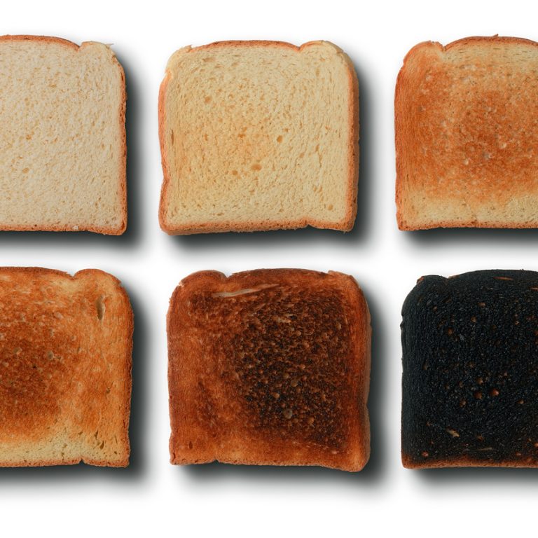 Seis rebanadas de pan con distintos grados de tostado, desde ligeramente doradas hasta quemadas, para representar el aumento de acrilamida durante el calentamiento.