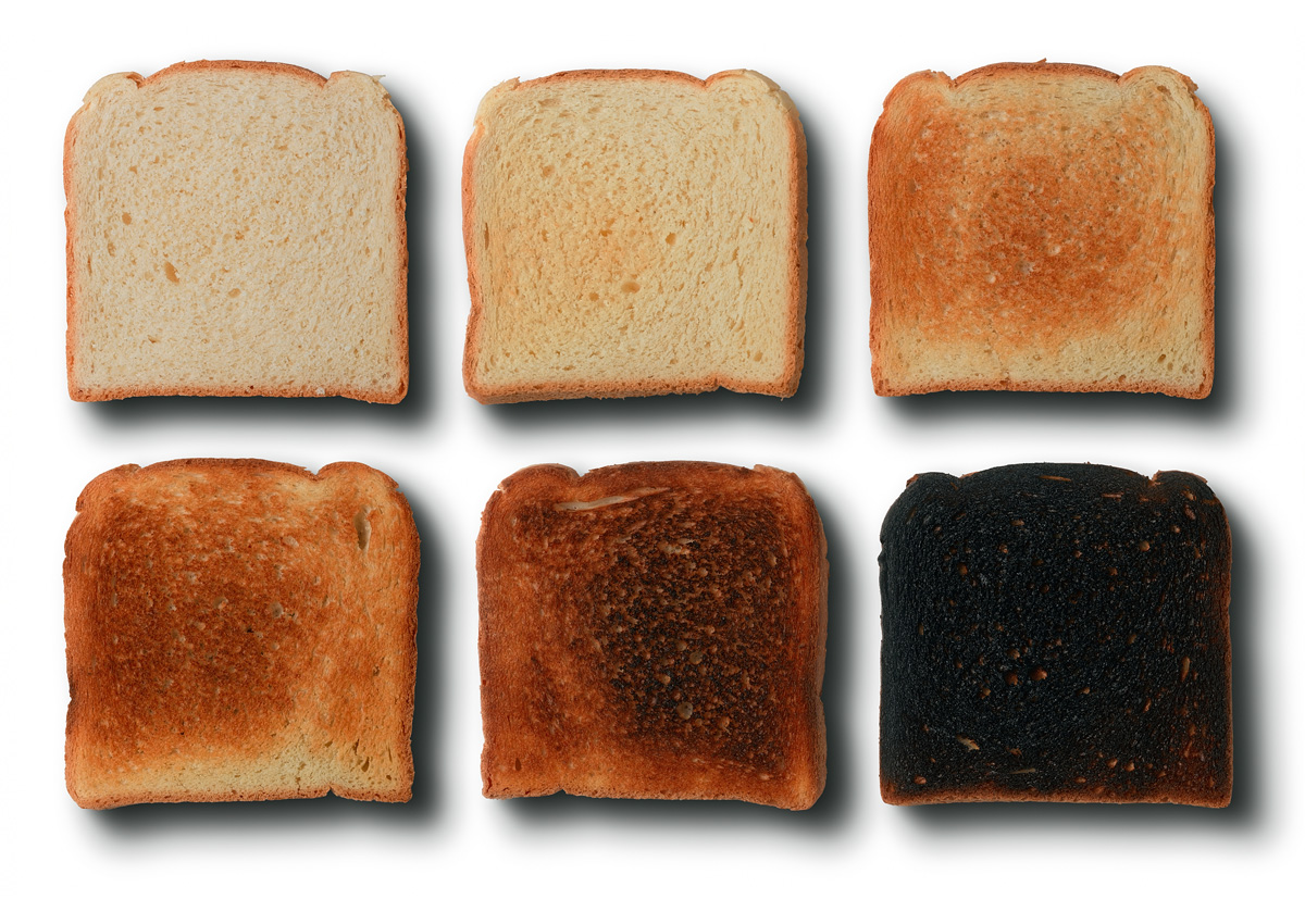 Seis rebanadas de pan con distintos grados de tostado, desde ligeramente doradas hasta quemadas, para representar el aumento de acrilamida durante el calentamiento.
