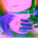 Manos con guantes morados sostienen arena de olivino, mineral utilizado en experimentos de captura de CO₂ mediante bacterias marinas modificadas.